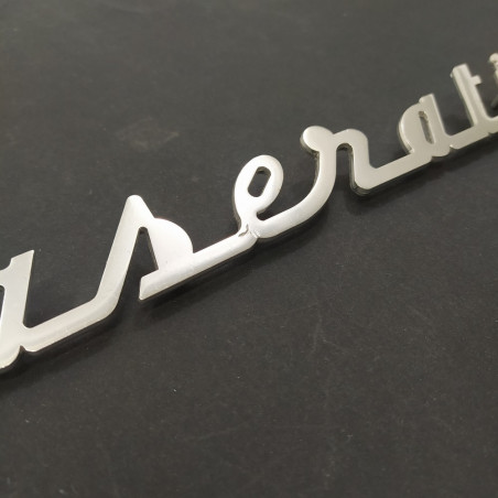 Originale scritta Maserati in metallo lucido, lunga 34 cm. Graffi di uso