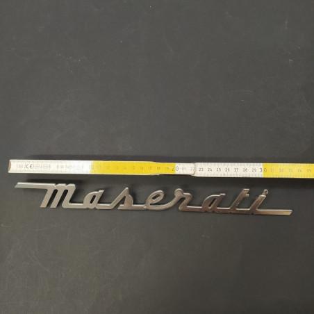 Originale scritta Maserati in metallo lucido, lunga 34 cm. Graffi di uso