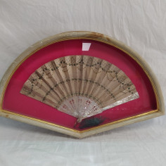 Ventaglio panna con decorazione verde e paiettes, sfondo fucsia. Vetro rotto