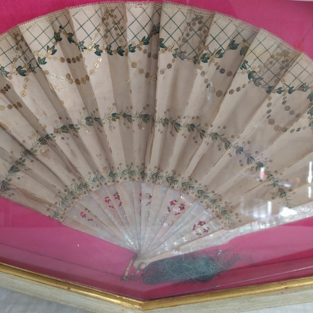 Ventaglio panna con decorazione verde e paiettes, sfondo fucsia. Vetro rotto