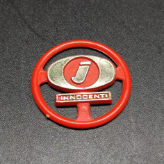 Fregio Innocenti in plastica rossa con dettagli dorati. Segni sul retro
