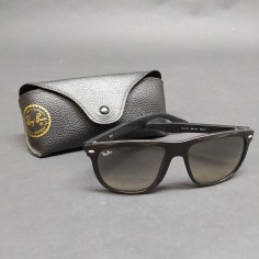 Occhiali da sole Ray-Ban con montatura nera in plastica, segni sulle lenti